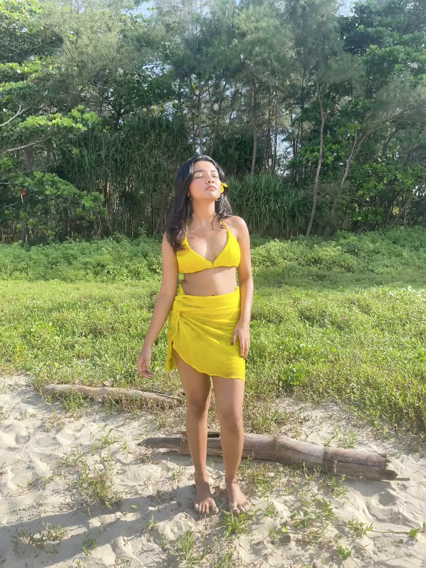 The model standing in the dunes in the yellow two-piece