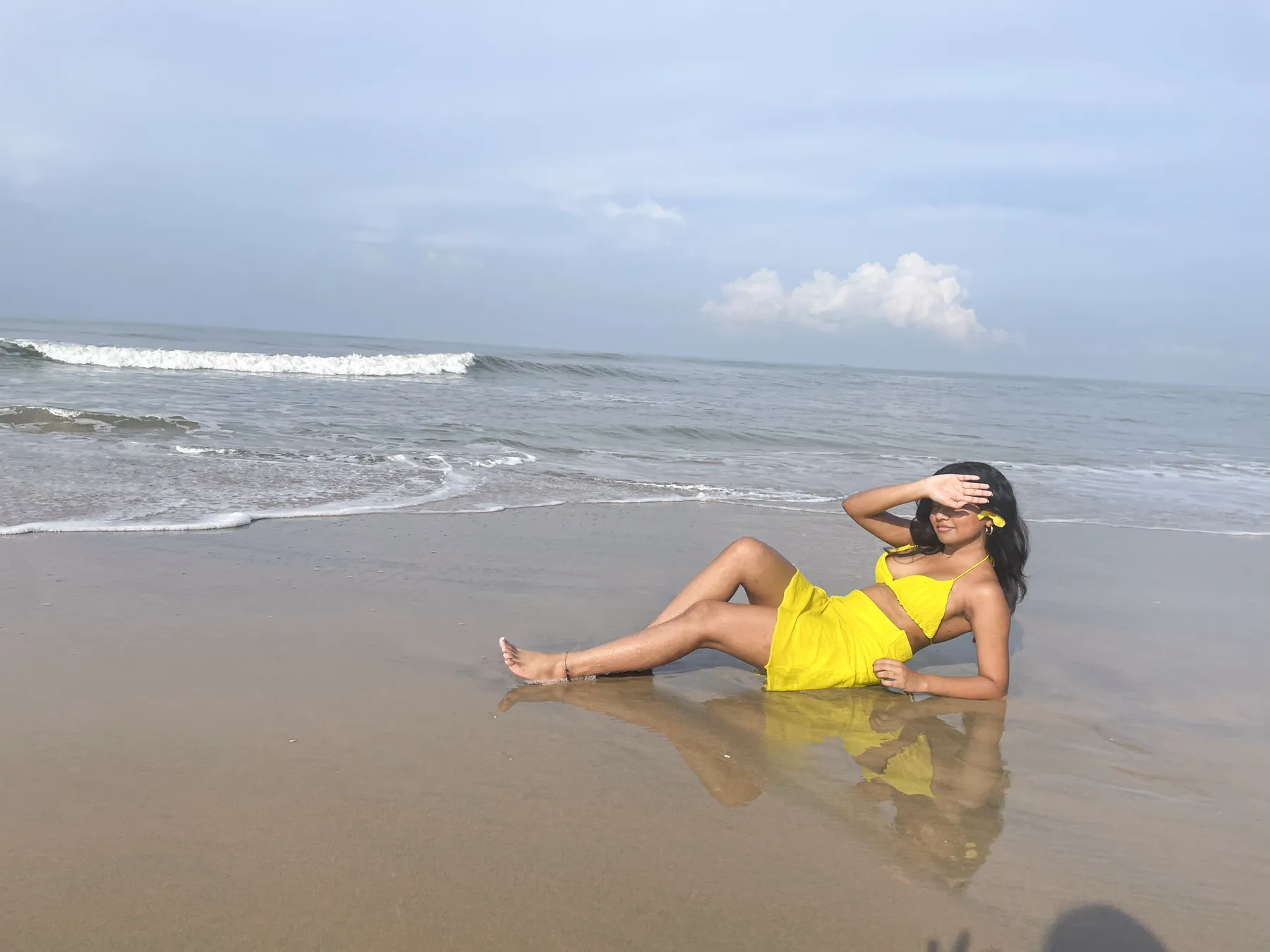 The model reclining on the wet sand at the water's edge