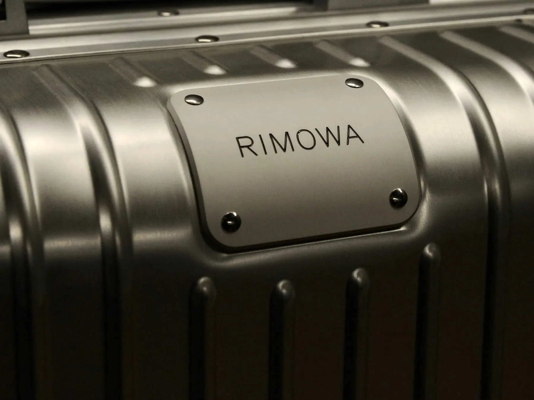 Close-up of a ribbed aluminium RIMOWA suitcase with its name plate